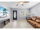 Living room featuring tile floor, a ceiling fan, a front door, a TV, and a leather couch at 212 N Bradford Ave, Tampa, FL 33609