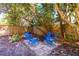 Cozy backyard with trees shading blue adirondack seating and providing a relaxing outdoor retreat at 3005 W Helen Ave, Tampa, FL 33611