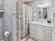 Stylish bathroom featuring a vanity with new countertops, decorative mirror, and tiled shower with patterned curtain at 3005 W Helen Ave, Tampa, FL 33611