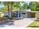Charming single-story home with a blue front door, mature trees, carport, and a well-maintained front yard at 3005 W Helen Ave, Tampa, FL 33611