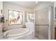 Bathroom featuring a soaking tub, glass-enclosed shower, and decorative window at 3023 Bent Creek Dr, Valrico, FL 33596
