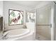 Bathroom featuring a soaking tub with a custom decorative window, and a separate glass enclosed shower at 3023 Bent Creek Dr, Valrico, FL 33596