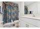 Well-lit bathroom with a modern vanity, white cabinets, and stylish blue floral shower curtain at 35029 Brackett Bnd, Zephyrhills, FL 33541