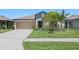 Charming single-story home with a well-manicured lawn, tropical landscaping, and attached two-car garage at 35029 Brackett Bnd, Zephyrhills, FL 33541