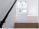 Light-filled staircase with dark handrail and view of the neighborhood through a large window at 3820 Pompano Se Dr, St Petersburg, FL 33705