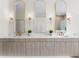 Modern bathroom vanity with dual sinks, elegant lighting fixtures, and ample storage with views of the glass-enclosed shower at 3982 Wellington Pkwy, Palm Harbor, FL 34685
