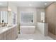 Bright bathroom with a freestanding tub, glass-enclosed shower, and a modern vanity with marble countertops at 3982 Wellington Pkwy, Palm Harbor, FL 34685