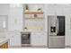 Modern kitchen featuring a wine cooler, stainless steel refrigerator, and floating shelves at 3982 Wellington Pkwy, Palm Harbor, FL 34685