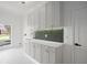 Bright laundry room featuring grey cabinets, gold hardware, and a mosaic tile backsplash at 3982 Wellington Pkwy, Palm Harbor, FL 34685