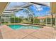 Screened-in pool area with brick patio, landscaping, and views of the backyard at 3982 Wellington Pkwy, Palm Harbor, FL 34685