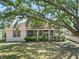 Exterior shot of the home showcasing the screened-in lanai and landscaped backyard with mature trees at 4317 74Th E Ave, Sarasota, FL 34243