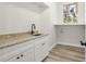 Functional laundry room with a sink, granite countertops, white cabinets, and a window at 4317 74Th E Ave, Sarasota, FL 34243