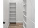 Walk-in closet featuring custom white shelving and wood-style flooring at 4317 74Th E Ave, Sarasota, FL 34243
