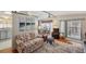 Cozy living room featuring a floral sofa, armchair, and access to a screened porch at 4801 Blanco Dr, Zephyrhills, FL 33541