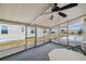 An enclosed sunroom with screened windows and a ceiling fan looks out to a grassy area at 4801 Blanco Dr, Zephyrhills, FL 33541