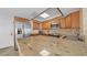 A bright kitchen has an island with stone counters, wood cabinets, and stainless steel appliances at 500 Treasure Island Cswy # 704, Treasure Island, FL 33706