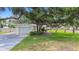 Garage exterior featuring a large driveway, lush lawn, and shaded by mature trees at 5055 29Th S St, St Petersburg, FL 33712