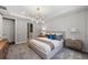 A well-lit bedroom with a gray plush carpet, featuring a modern bed, stylish lighting, and ample closet space at 5953 Bluestar Ct, Lakewood Ranch, FL 34211