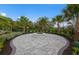Community fire pit area with modern pavers, surrounded by lush landscaping and palm trees at 5953 Bluestar Ct, Lakewood Ranch, FL 34211