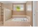Bathtub and shower featuring tile accents and glass block window at 6407 E 112Th Ave, Temple Terrace, FL 33617