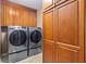Laundry room features a washer, dryer and custom wooden cabinets for storage at 6407 E 112Th Ave, Temple Terrace, FL 33617