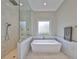 Modern bathroom with walk-in shower and a freestanding tub under a large window at 715 Pinckney Dr, Apollo Beach, FL 33572