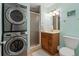 Functional bathroom with a shower, vanity, commode, and stacked washer and dryer at 7540 Sunshine Skyway S Ln # 219, St Petersburg, FL 33711
