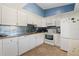 Efficient kitchen with white cabinets, stainless steel appliances, blue backsplash, and tile flooring at 7540 Sunshine Skyway S Ln # 219, St Petersburg, FL 33711