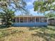 Exterior view of the backyard featuring a screened-in patio and mature trees at 8014 N Lynn Ave, Tampa, FL 33604