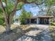 Charming single-story home with covered parking, mature trees, and a vibrant red front door at 8014 N Lynn Ave, Tampa, FL 33604