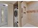 A modern bathroom with a stacked washer/dryer and tiled walk-in shower with grab bar at 855 Bayway Blvd # 703, Clearwater Beach, FL 33767