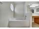 Bright bathroom with a large soaking tub situated beneath a unique geometric window that provides natural light at 10409 Fly Fishing St, Riverview, FL 33569