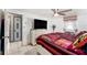 Bedroom with a tile floor, ceiling fan, television on the dresser, and an adjoining bathroom through a doorway at 10737 Scenic Dr, Port Richey, FL 34668