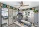 Exercise room featuring a ceiling fan, treadmill, sliding glass doors, window with curtains, and a rug on the tile floor at 10737 Scenic Dr, Port Richey, FL 34668