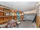 Garage featuring shelves, a vintage chair, a ladder, fan, and lawn mower with a concrete floor and exposed rafters at 10737 Scenic Dr, Port Richey, FL 34668