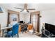 Home office with two windows, a ceiling fan, a desk with computer equipment, and an adjacent blue cushioned chair at 10737 Scenic Dr, Port Richey, FL 34668