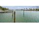Scenic waterfront view with dock pilings and palm trees lining the canal under a cloudy blue sky at 11340 5Th E St, Treasure Island, FL 33706