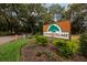 Welcome to Raintree Village sign with mature trees and lush landscaping at community entrance at 11708 Raintree Village Blvd # A, Temple Terrace, FL 33617