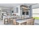 Bright dining area with a table for six, wicker chairs, and a modern light fixture, next to the open kitchen at 13253 Tropical Breeze Way, Hudson, FL 34669