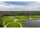 An aerial view of a community park with a dog park, parking lot, and a walking path around a pond at 13608 S Village Dr # 6203, Tampa, FL 33618