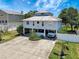 Aerial view of stilt home with metal roof, large driveway, and lush landscaping at 13974 75Th Ave, Seminole, FL 33776