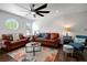 A cozy living room showcases rich wood floors, supple leather seating, and unique window design that brings the outside in at 13974 75Th Ave, Seminole, FL 33776