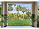 Framed view of the backyard showing lush greenery and majestic palm trees under a blue sky at 1476 Harbour Walk Rd, Tampa, FL 33602