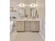 Bright bathroom featuring dual vanities with stylish mirrors, modern lighting, and neutral decor at 15635 Starling Water, Lithia, FL 33547