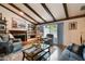 Cozy living room featuring exposed beam ceilings, a brick fireplace, and hardwood flooring at 16503 W Course Dr, Tampa, FL 33624