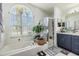 Bright bathroom with a garden tub beneath a large arched window and a separate glass shower at 18013 Palm Breeze Dr, Tampa, FL 33647