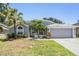 Charming single-story home with a well-manicured lawn, mature palm trees, and a welcoming front entrance with a seafoam green door at 18013 Palm Breeze Dr, Tampa, FL 33647