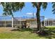Backyard view of a screened lanai with mature trees, plants, and green grass at 19129 Lake Audubon Dr, Tampa, FL 33647