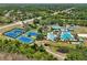 An aerial shot showcases tennis courts and multiple pools with inviting lounge areas amidst lush landscaping at 19129 Lake Audubon Dr, Tampa, FL 33647