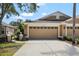 Home's two-car garage with decorative windows, manicured lawn, and walkway to front door at 19129 Lake Audubon Dr, Tampa, FL 33647
